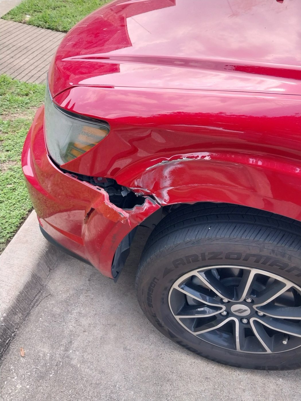 Damage to the front corner and wheel arch of a red SUV.
