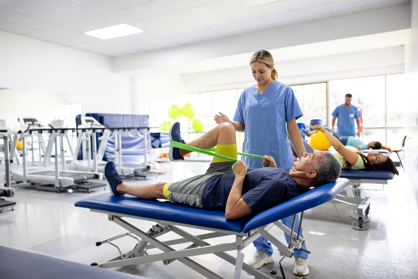 Physical therapist guiding a patient through resistance band exercises during a rehabilitation session at a clinic