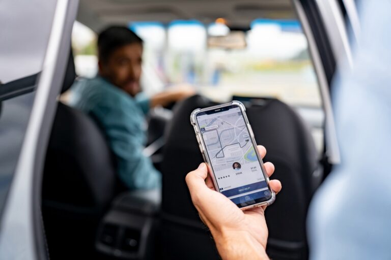 Passenger in the back of a rideshare car in Texas holding a phone showing the ride app and driver details