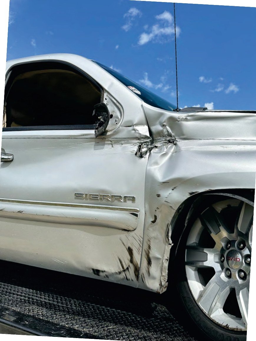 Close view of the crushed front fender and wheel arch of a silver pickup.